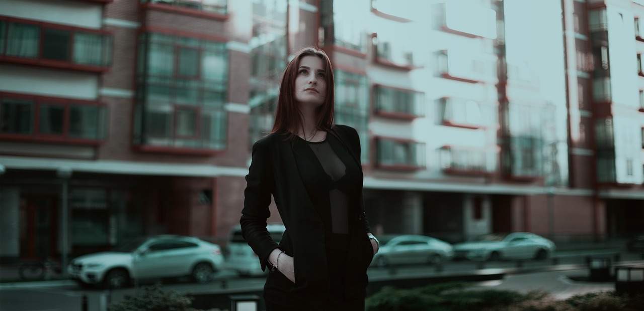 a woman standing in front of a tall building, inspired by Elsa Bleda, woman in black business suit, attractive girl, in a suburb, anton fadeev 8 k