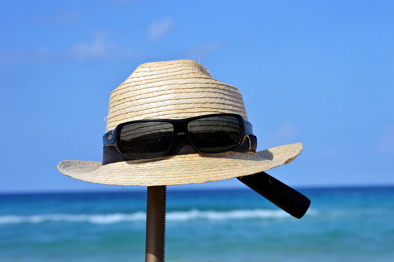 a hat and sunglasses on a pole at the beach, a picture, by Edward Corbett, pixabay, realism, visor covering eyes, heat wave, instrument, waist - shot