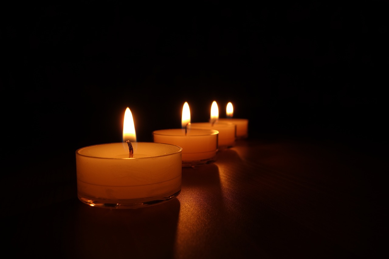 a row of lit candles sitting on top of a table, a picture, shutterstock, dark scene with dim light, stock photo, four, where being rest in peace