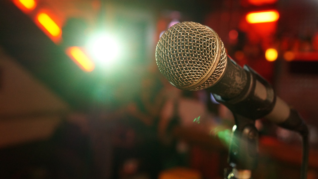 a close up of a microphone on a stand, a picture, happening, brightly-lit, pub, where a large, exaggerated accents