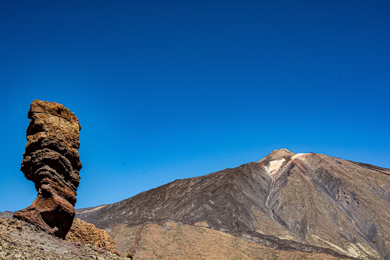 a rock formation with a mountain in the background, by Altichiero, unsplash, figuration libre, lava!!!, clear blue skies, iso 1 0 0 wide view, banner