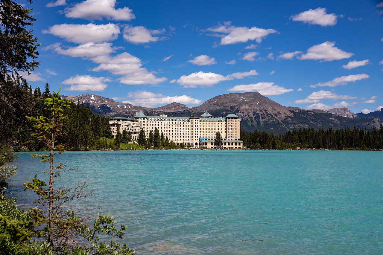 a large building sitting in the middle of a lake, by Brigette Barrager, shutterstock, behind that turquoise mountains, hotel, - - ar 9 : 1 6, canada