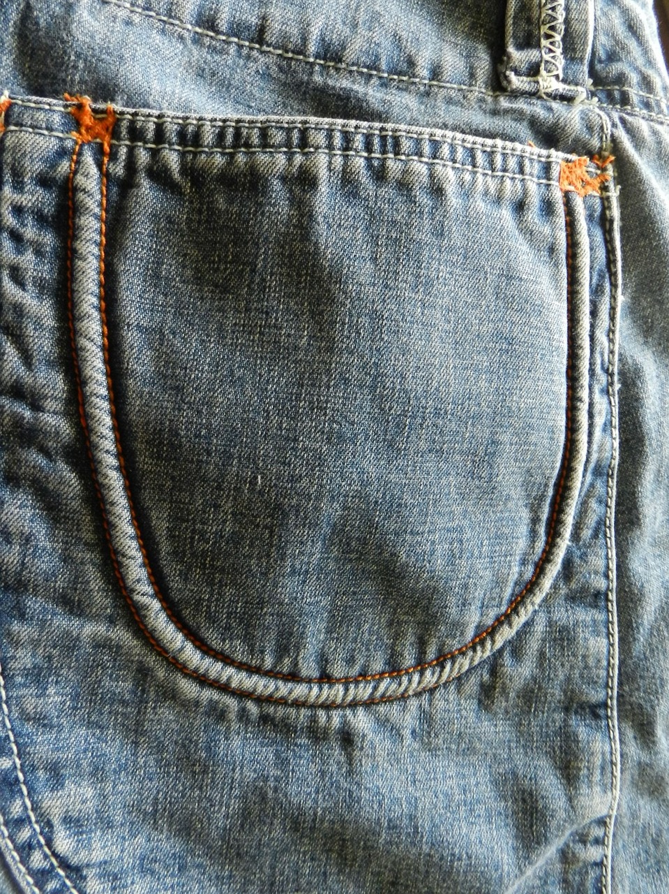the back pocket of a pair of jeans, a macro photograph, sōsaku hanga, blue!! with orange details, half body photo, uncut, visible stitching