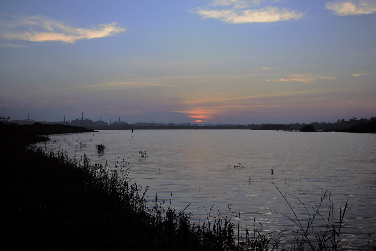 a body of water with a sunset in the background, sōsaku hanga, water reservoir, landscape of flat wastelands, ruanjia, flash photo
