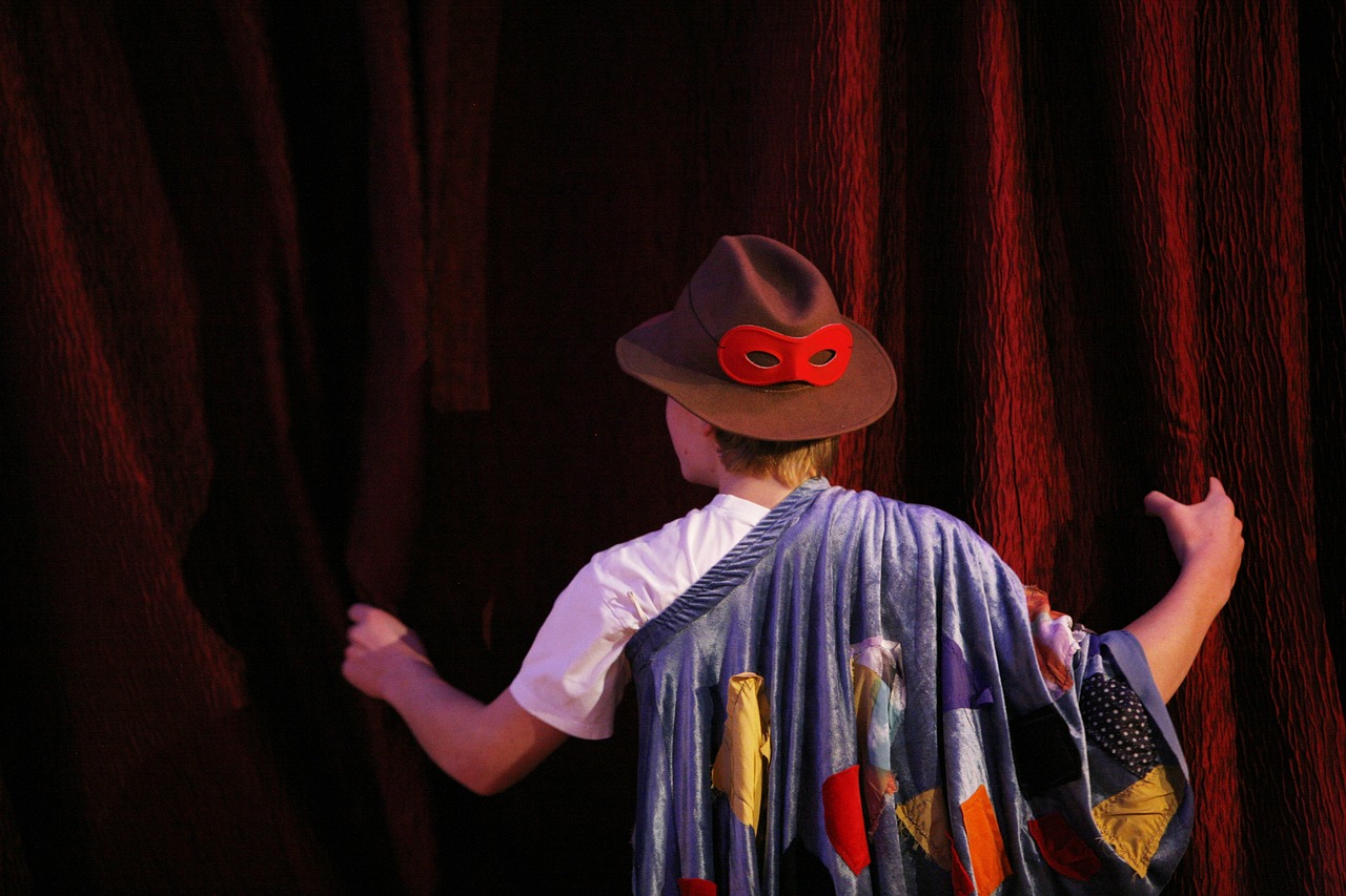 a little boy that is standing in front of a curtain, by Alison Watt, flickr, figuration libre, jester hat, backside of scenography elements, wearing a barca cape, action shot