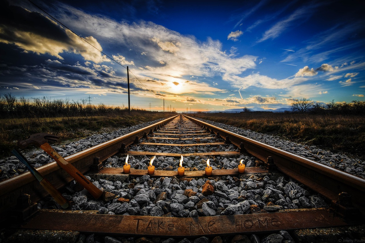 a train track with a sunset in the background, a picture, realism, blue sky, low angle photography, sparsely populated, yard