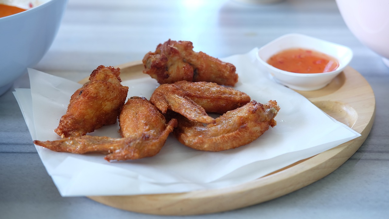 a white plate topped with fried food next to a bowl of dipping sauce, by Yi Insang, pixabay, hurufiyya, angel wings, rounded beak, morning detail, shot on leica sl2