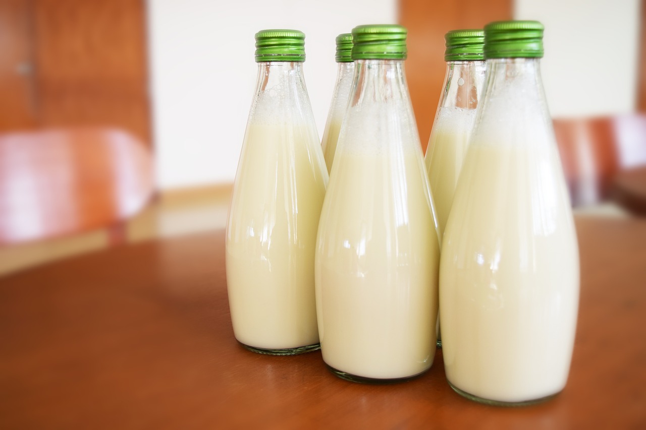 three bottles of milk sitting on a table, by Juan O'Gorman, shutterstock, green, in a row, soft - warm, round bottle