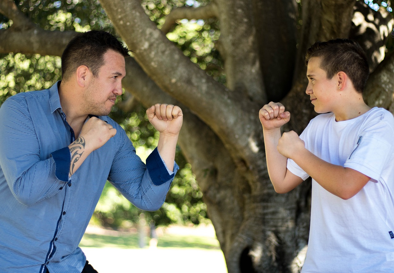 a man standing next to a boy in front of a tree, a portrait, inspired by Samuel Silva, pexels, in a fighting stance, arm wrestling, lachlan bailey, in an action pose