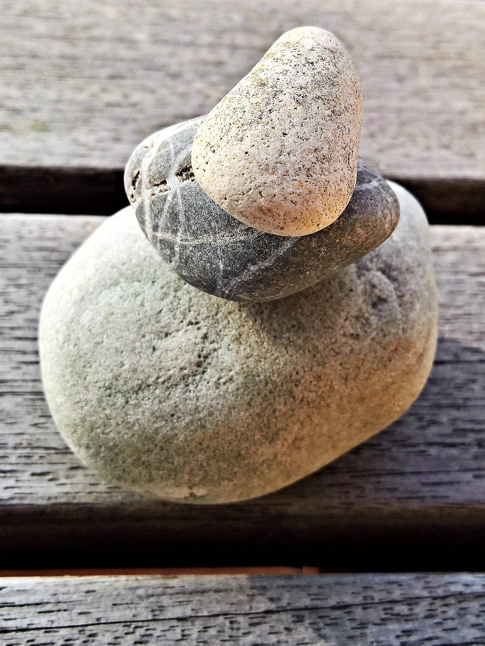 a stack of rocks sitting on top of a wooden bench, a macro photograph, iphone capture, gourd, very stylized, peace