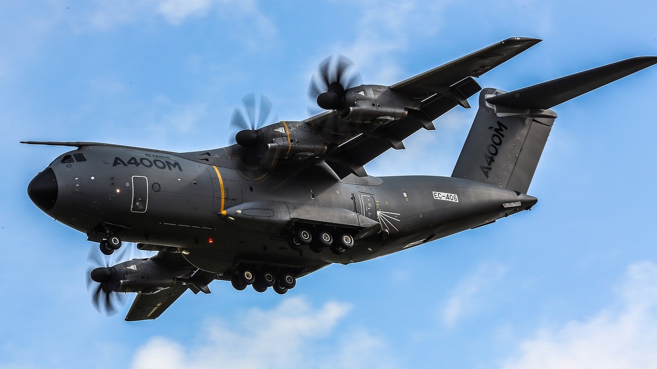 a large air plane flying through a blue sky, a portrait, by Miklós Borsos, pixabay, hurufiyya, black wings instead of arms, himars, outside on the ground, huge veins