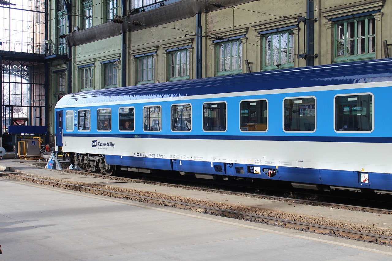 a blue and white train parked in front of a building, shutterstock, view from the side”, platform, carl gustav, accompanying hybrid