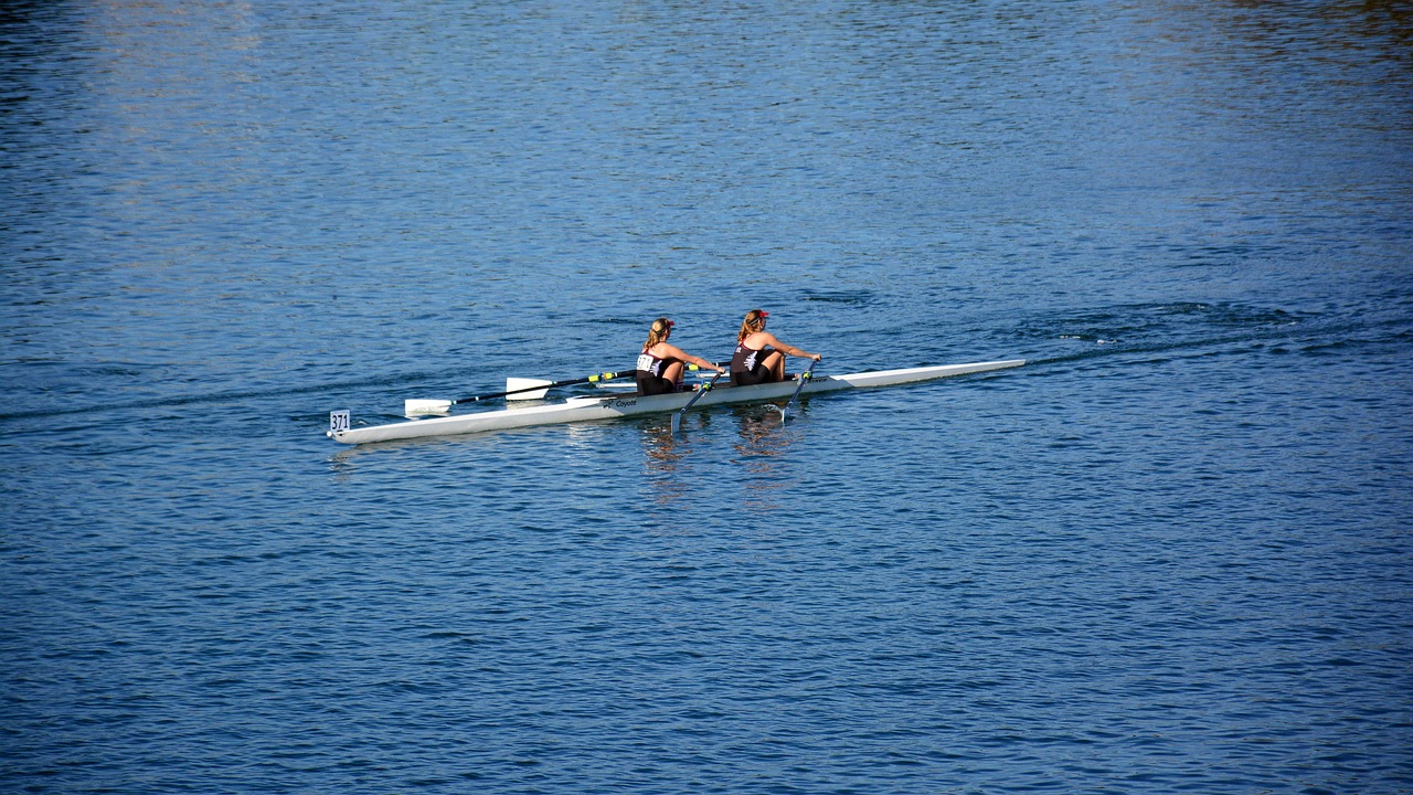 a couple of people riding on top of a boat, by Nancy Spero, flickr, sculls, sport, beautiful sunny day, adult pair of twins