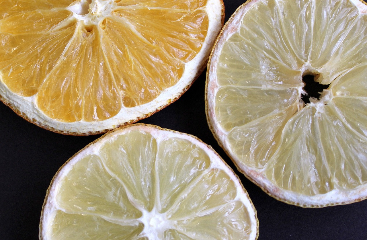 a couple of slices of lemon sitting on top of a table, a picture, by Carey Morris, pexels, process art, orange skin. intricate, luminescence，highly detailed, dead fruits, photo of a beautiful