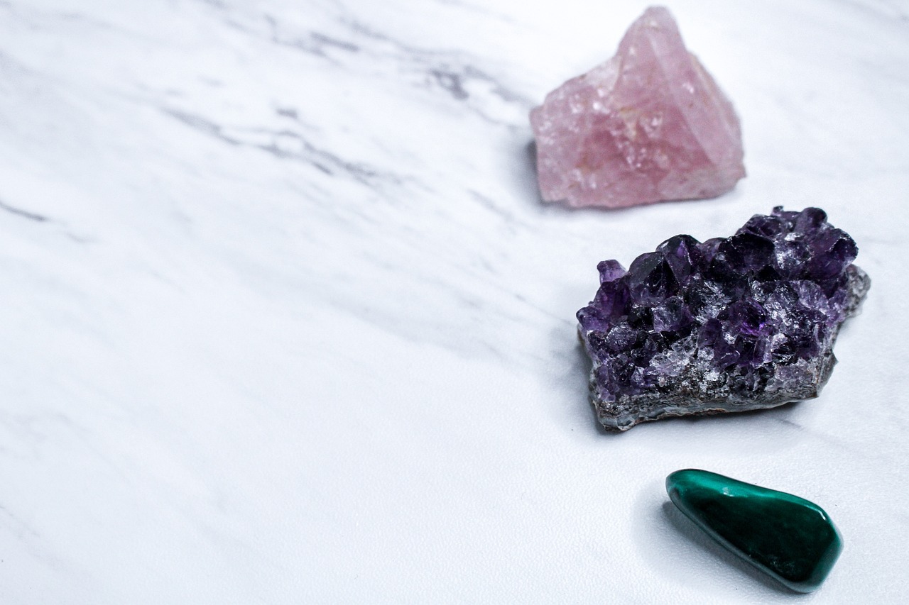a couple of crystals sitting on top of a table, a picture, trending on pexels, minimalism, purple and green, various items, crushed, on a white table