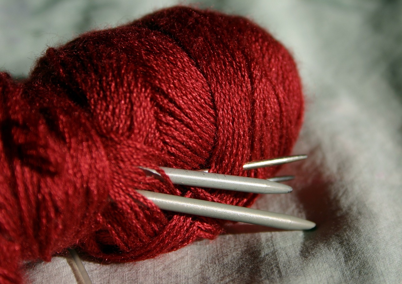 a red ball of yarn next to two knitting needles, by Eugeniusz Zak, flickr, silver red, silk, spikes, taken with a pentax1000