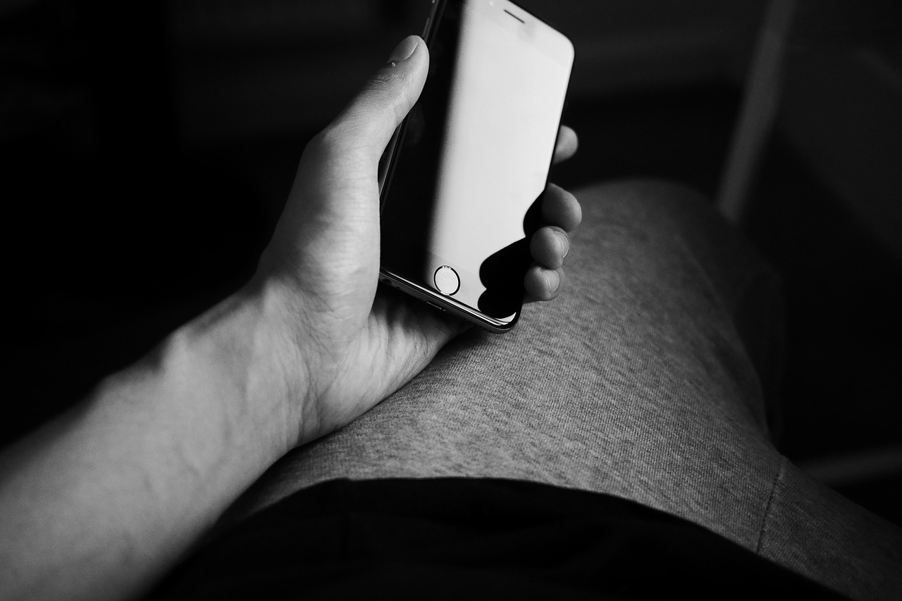 a person holding a cell phone in their hand, a black and white photo, resting, flesh with technology, back - lit, an ultra realistic