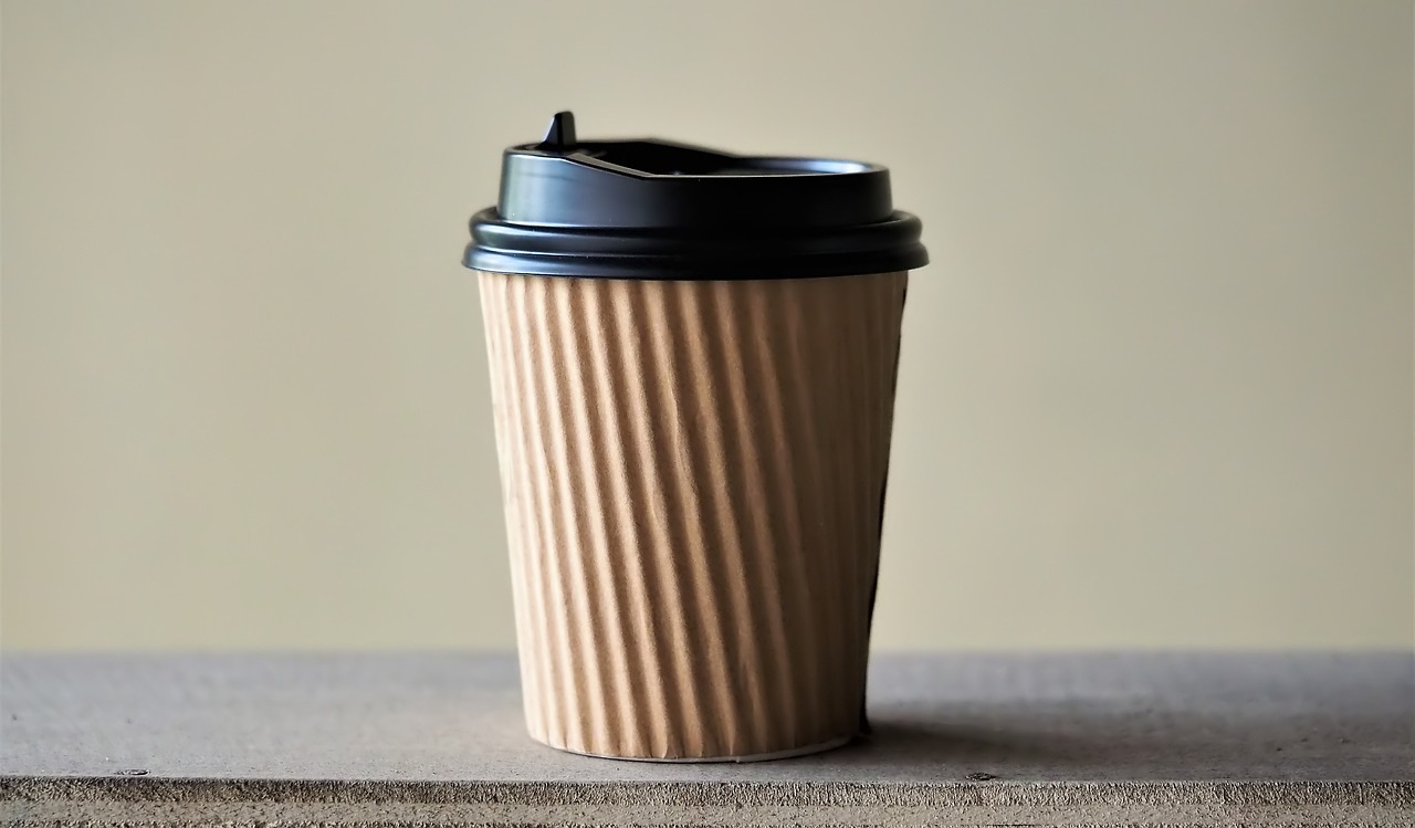 a coffee cup sitting on top of a table, by Yasushi Sugiyama, shutterstock, minimalism, black fine lines on warm brown, paper cup, high detail product photo, close up shot a rugged