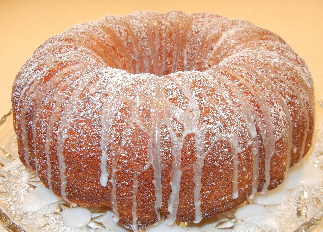 a bundt cake sitting on top of a glass plate, by Jim Nelson, detailed zoom photo, powdered sugar, file photo, rum