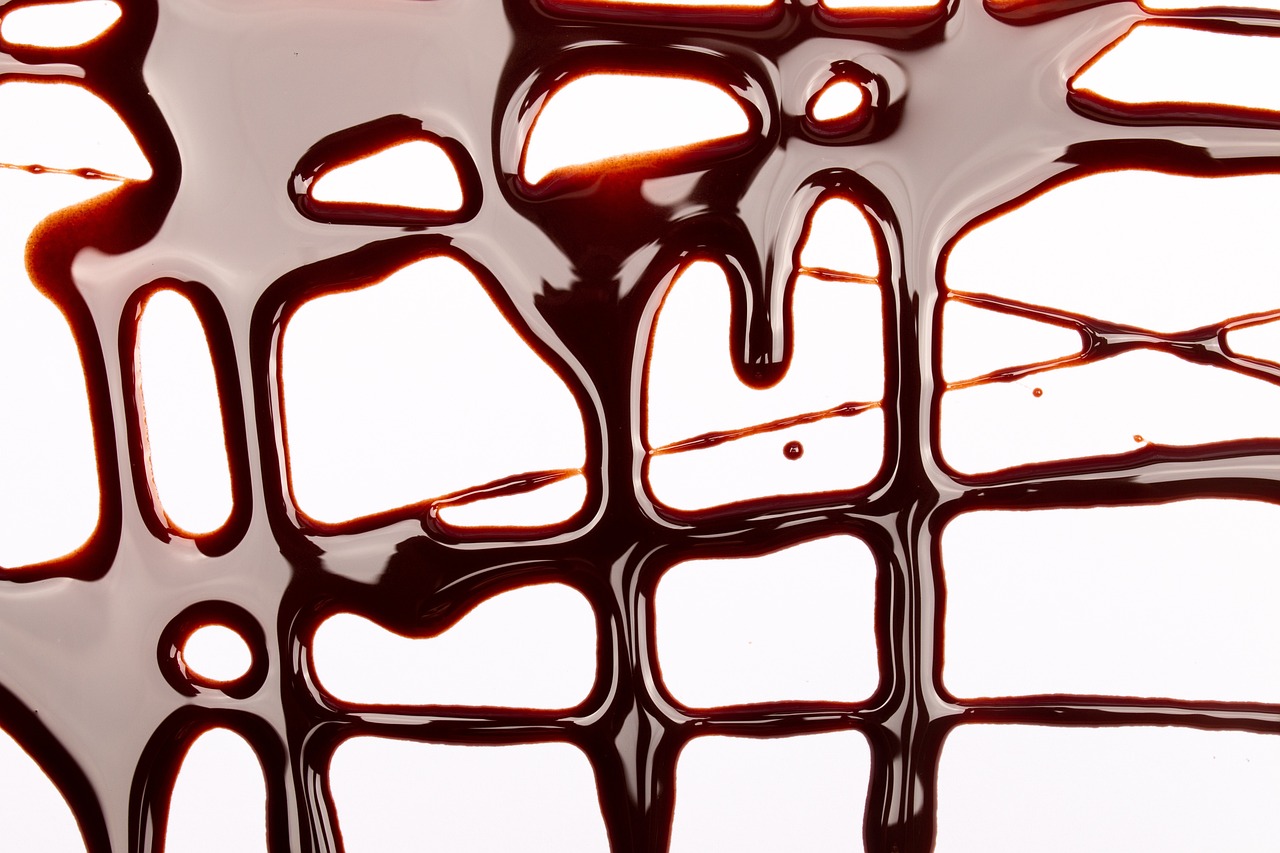 a piece of chocolate sitting on top of a table, by Andrei Kolkoutine, abstract illusionism, syrup, close-up product photo, detailed grid as background, blood