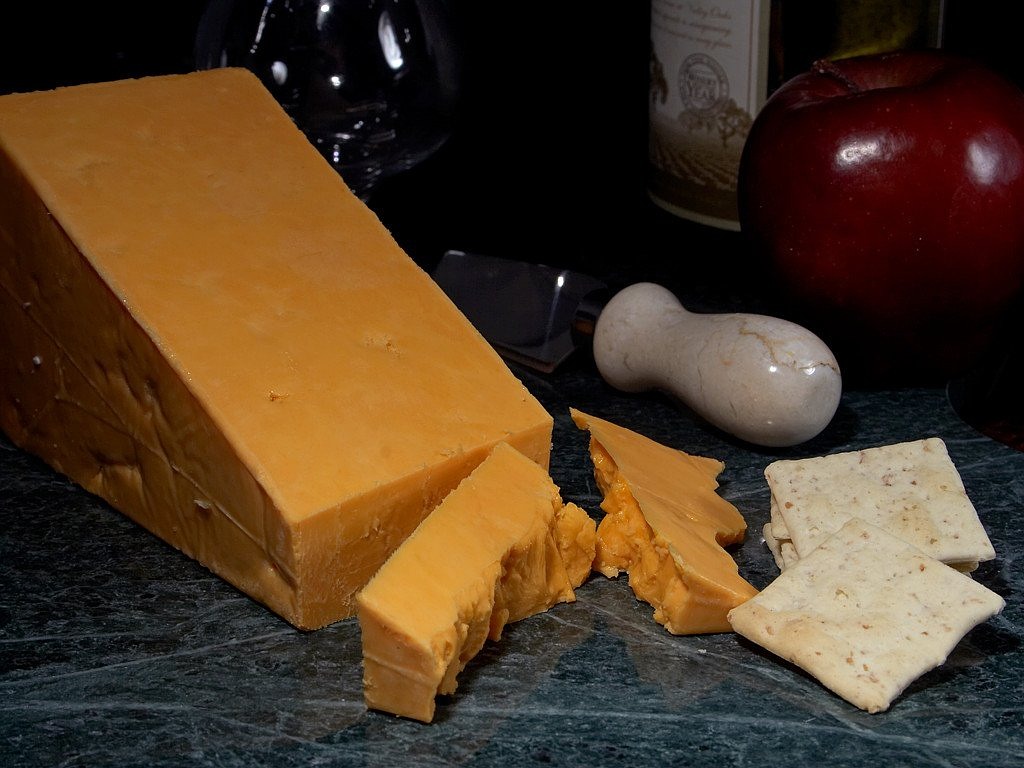 a block of cheese sitting on top of a counter next to crackers, by David Garner, photorealism, wikimedia, buffalo, orange extremely coherent, long snout