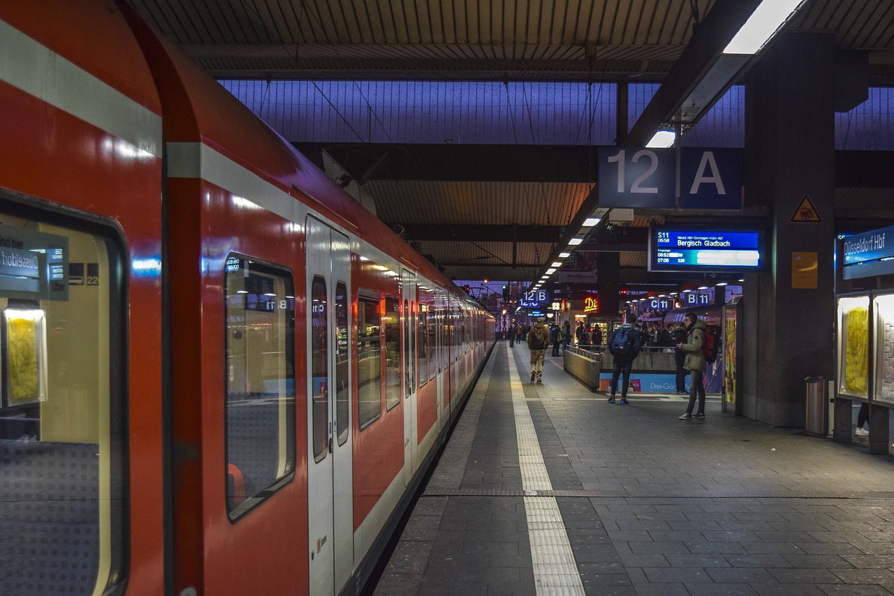 a red and white train pulling into a train station, a picture, by Hans Schwarz, shutterstock, blue and red lighting, people at night, stock photo, berlin
