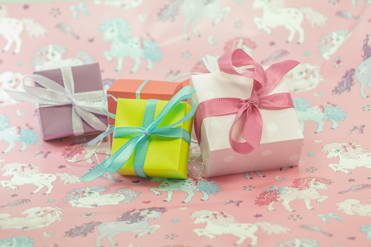 a couple of gift boxes sitting on top of a table, a stock photo, by Alice Mason, shutterstock, unicorns, green and pink colour palette, closeup photo, birthday wrapped presents