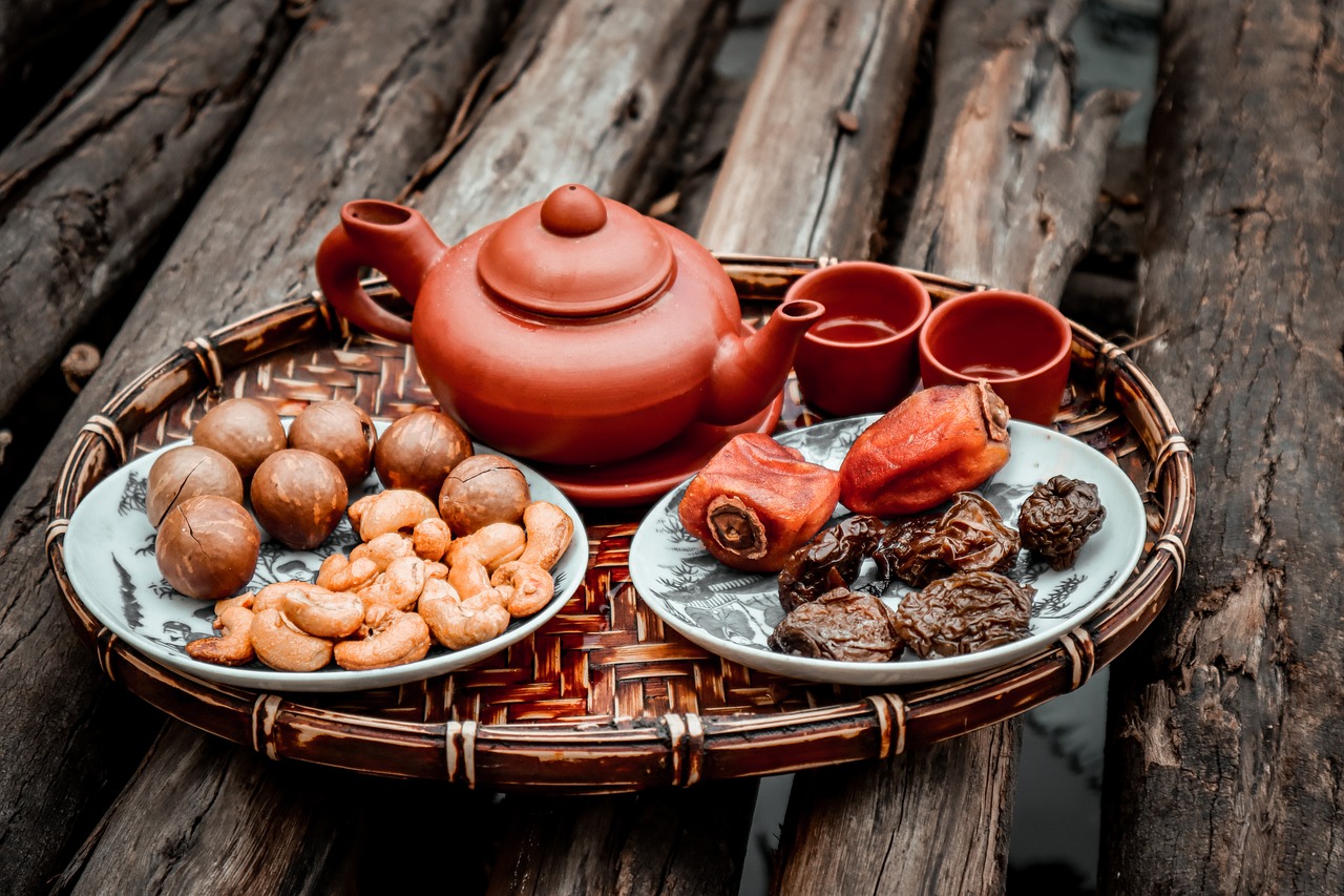 a tray of food sitting on top of a wooden table, a still life, by Shen Quan, pexels, dau-al-set, assam tea village background, red lanterns, 💣 💥, clay amulets