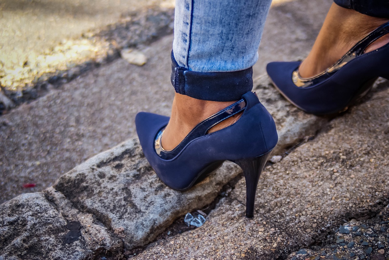 a close up of a person wearing high heels, by Niko Henrichon, pexels, stylish navy blue heels, standing in township street, 💋 💄 👠 👗, bottom angle