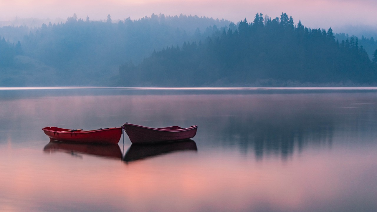 a couple of red boats sitting on top of a lake, a picture, by Ivan Grohar, ethereal mist, calm colors, benjamin vnuk, lined up horizontally