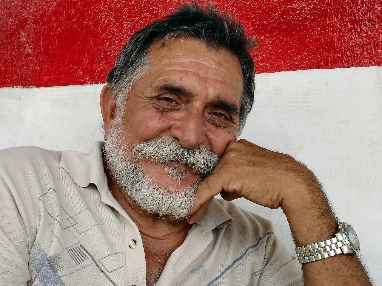 a close up of a person wearing a watch, a portrait, cuban setting, short white beard, very very happy, flag