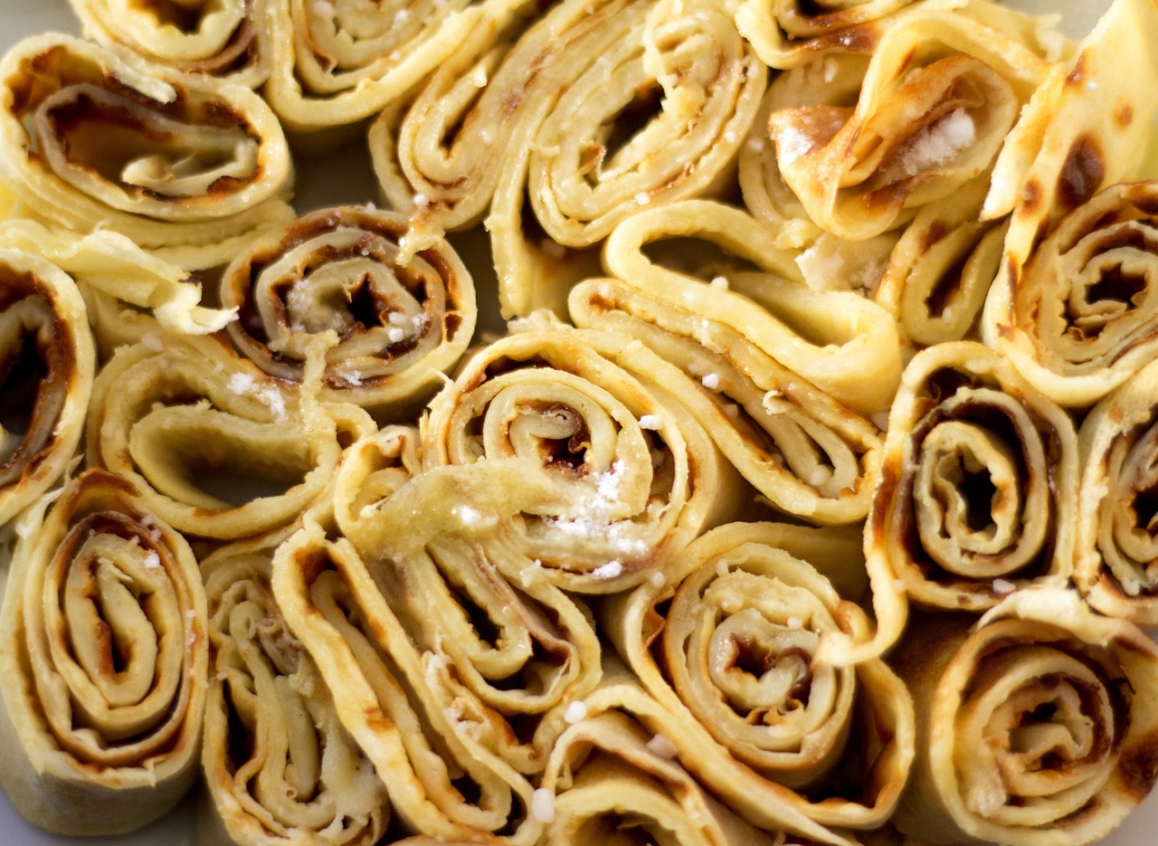 a plate that has some very tasty looking food on it, inspired by Géza Dósa, renaissance, in the shape of a cinnamon roll, detail texture, pancakes, petals