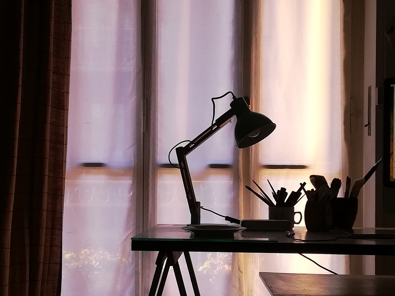 a lamp sitting on top of a desk next to a window, by Andrei Kolkoutine, pexels, detailed silhouette, cinematic shot!, art workstation, studyng in bedroom