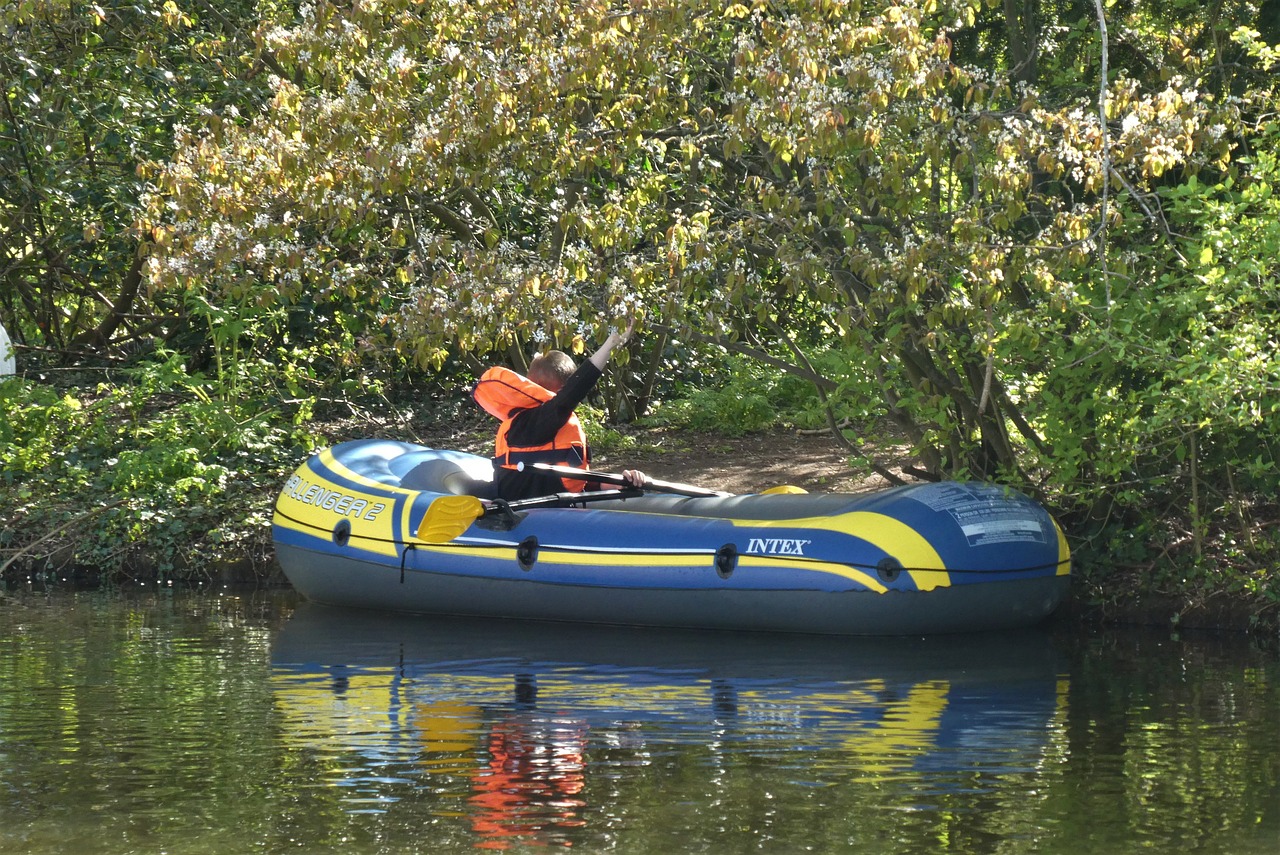 a man in an inflatable raft paddling down a river, a photo, by Istvan Banyai, esher, dingy gym, family friendly, boat
