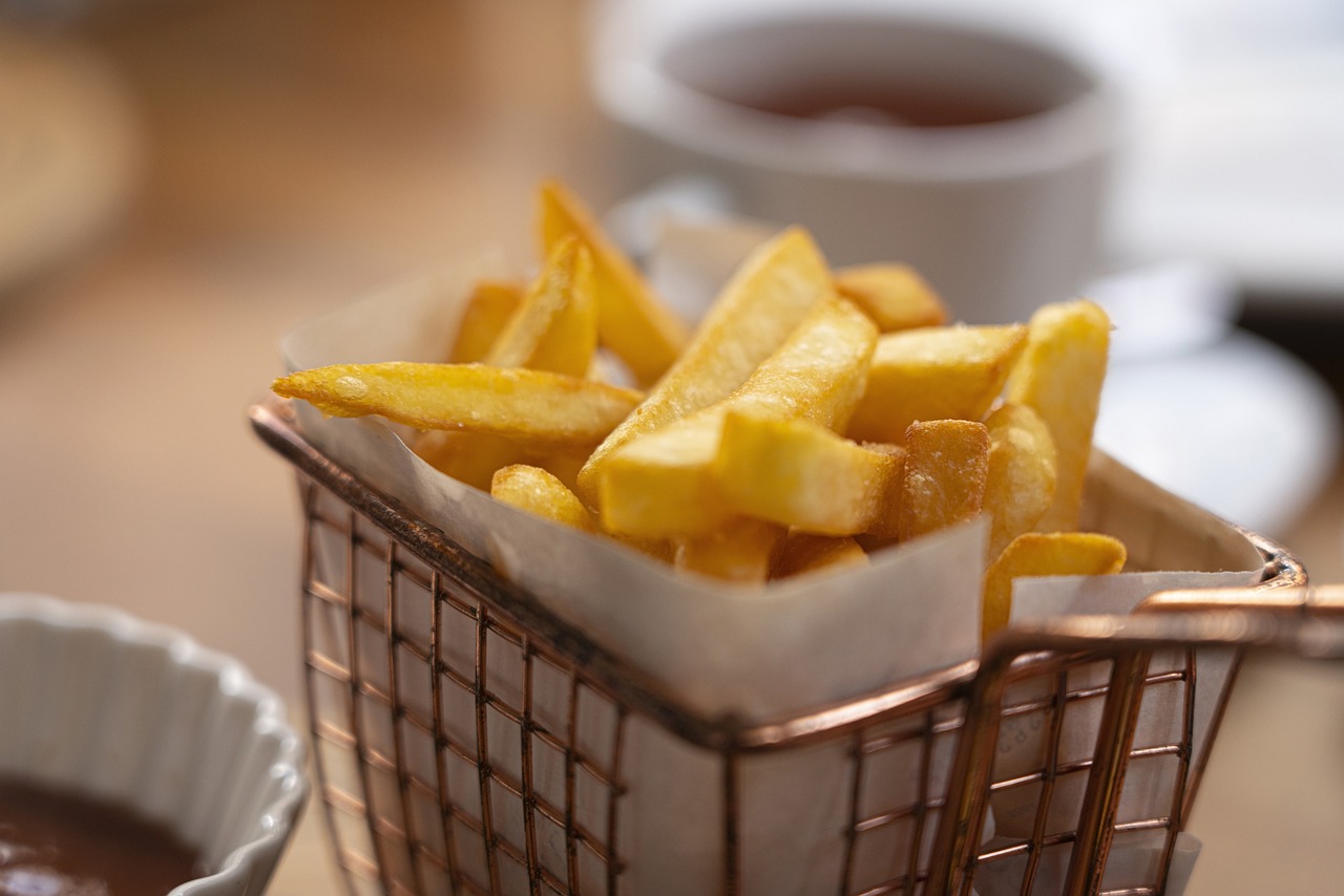 a basket filled with french fries next to a cup of coffee, a stock photo, inspired by Pia Fries, soft natural lighting, gold, closeup at the food, tea