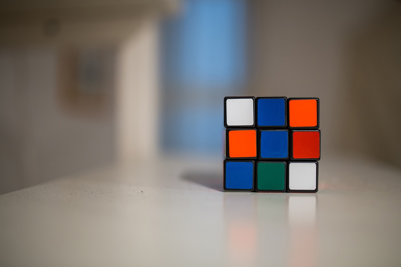 a rubik cube sitting on top of a table, a picture, inspired by Ernő Rubik, unsplash, soft geometry, taken with my nikon d 3, strong blue and orange colors, compute shader