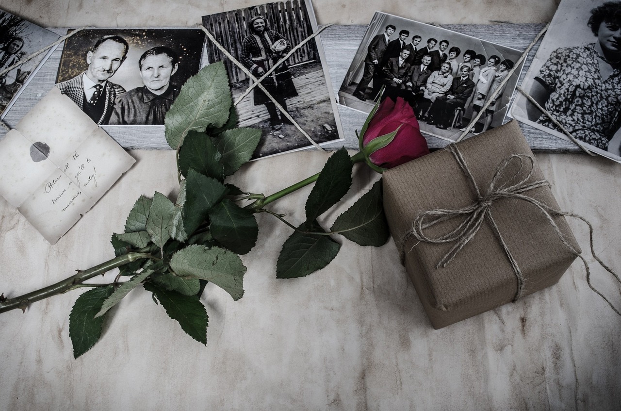 a bunch of photos sitting on top of a table next to a rose, a black and white photo, gifts, deteriorated, profile picture, romanian