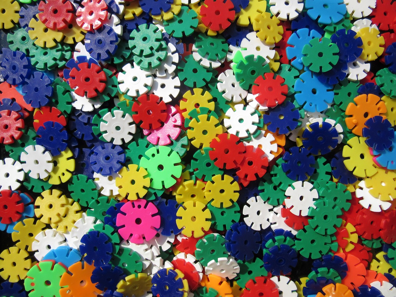 a pile of colorful gears sitting on top of a table, inspired by Howardena Pindell, flickr, kinetic pointillism, snowflakes, plastic texture, full of colour 8-w 1024, flower motif