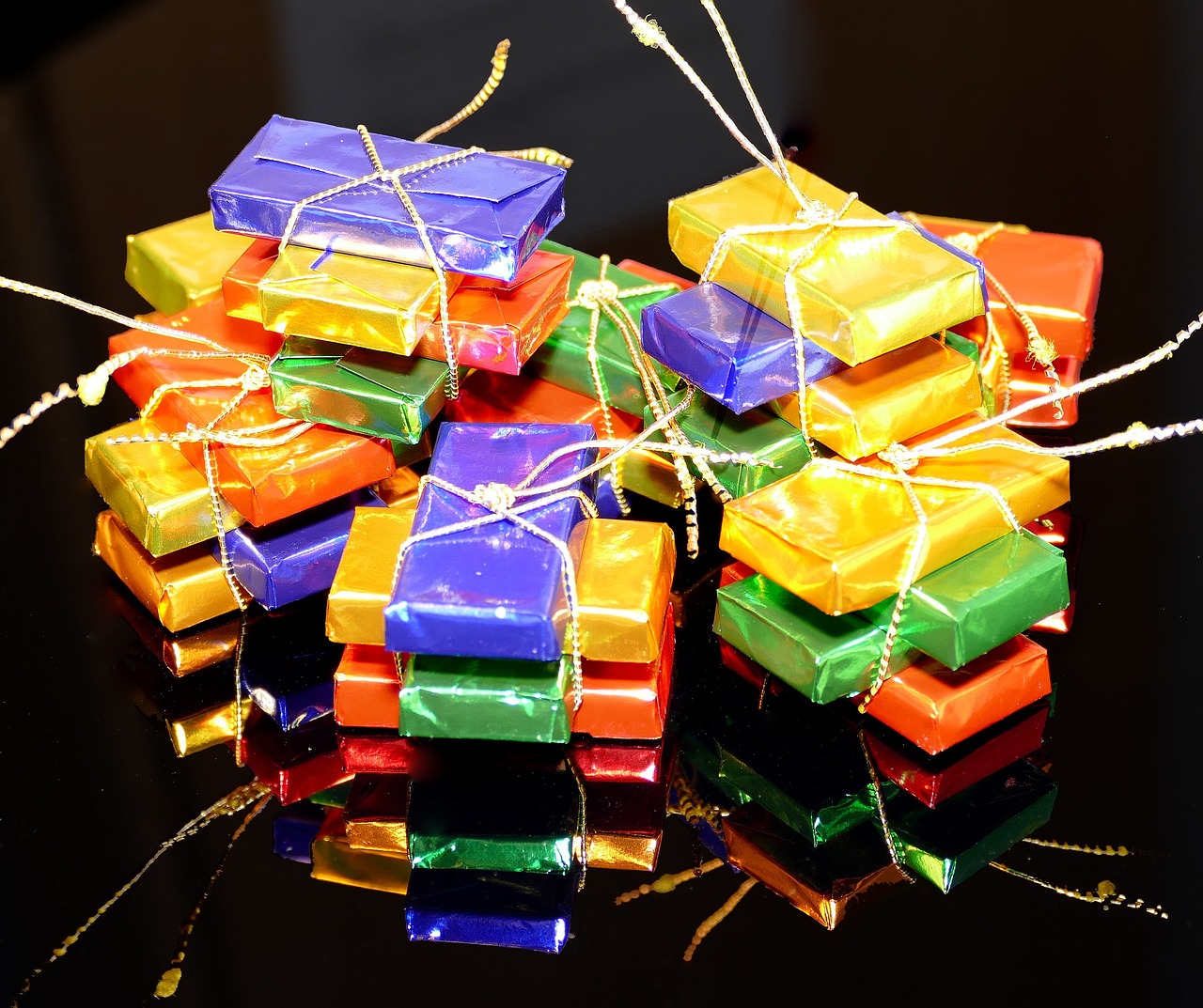 a bunch of wrapped presents sitting on top of a table, by Dietmar Damerau, happening, chocolate candy bar packaging, layers of colorful reflections, strings, with a black background