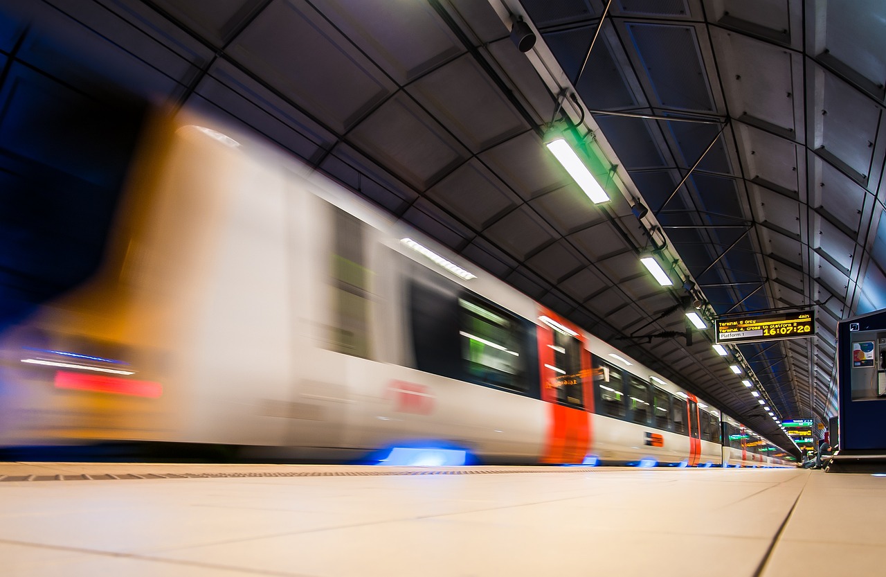 a train traveling through a train station next to a platform, a picture, by Thomas Häfner, shutterstock, speeding through london, whirling gasses, stock photo, rack focus