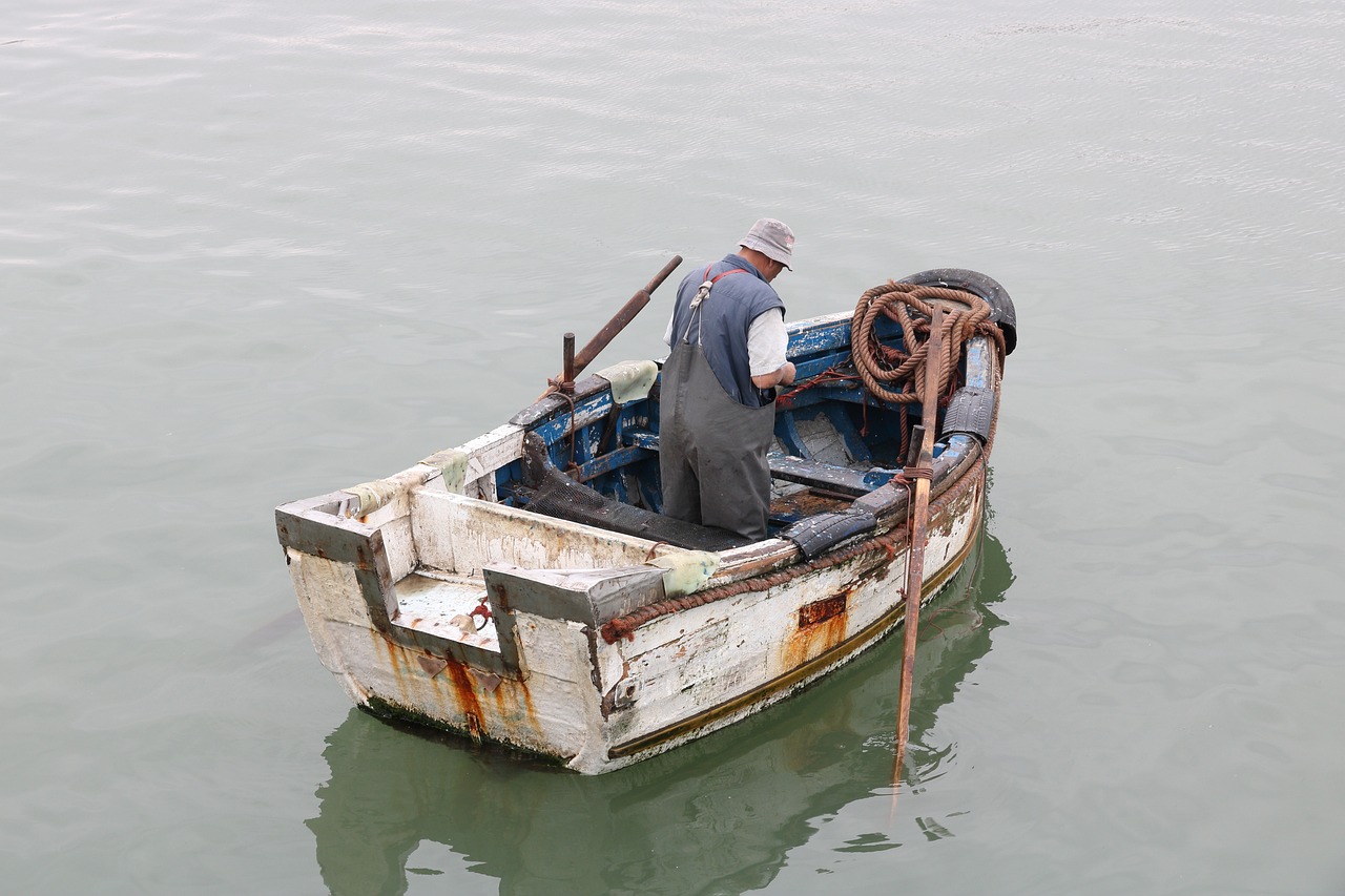 a man sitting in a small boat in the water, by Francesco Raibolini, flickr, repairing the other one, moldy, hooked - up, dad