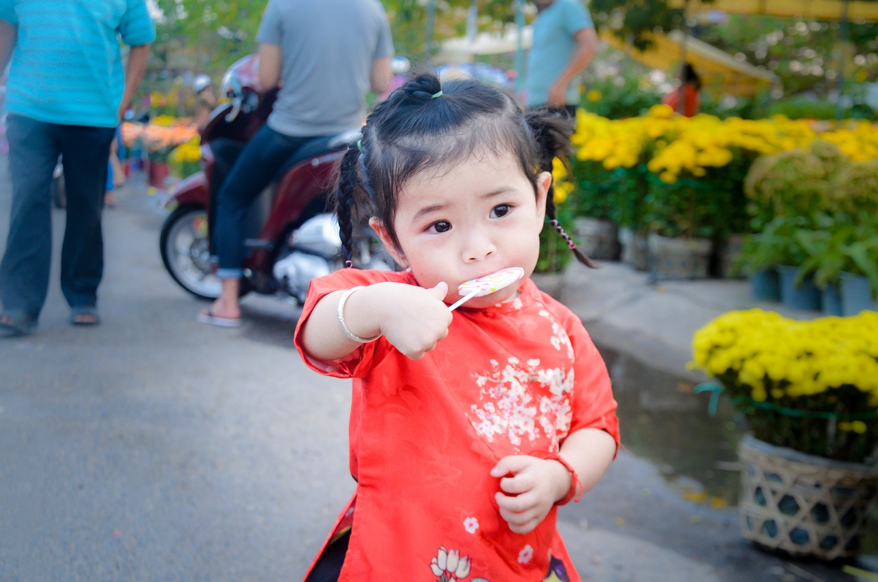a little girl in a red dress brushing her teeth, a picture, by Yi Insang, shutterstock, with street food stalls, phuoc quan, cute beautiful, stock photo