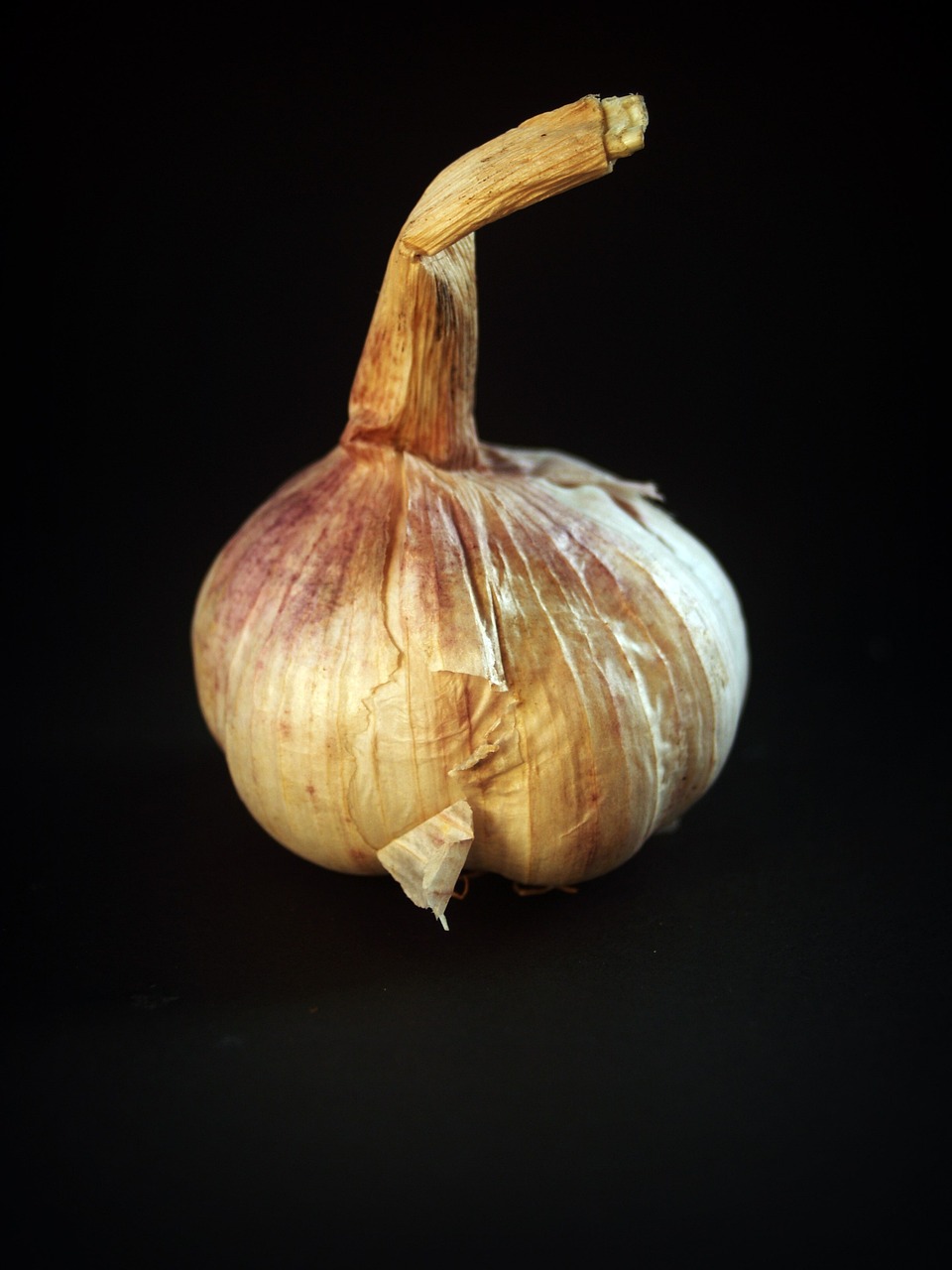 a bulb of garlic on a black background, a macro photograph, hyperrealism, miniature product photo, high detail product photo, turned back to camera, fully body photo