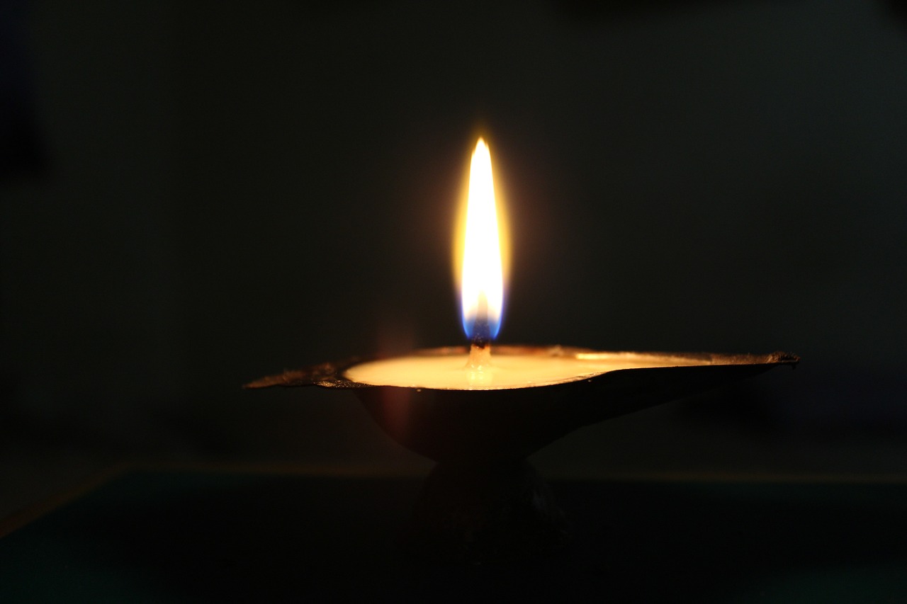 a lit candle sitting on top of a table, hurufiyya, light from bottom, wikimedia, a close up shot, light coming from above