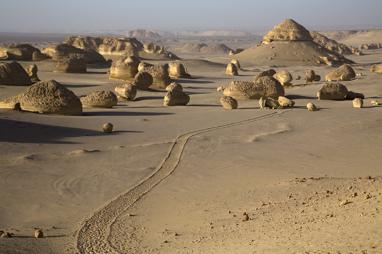 a group of rocks sitting in the middle of a desert, by Dietmar Damerau, land art, sphinx in distance, high res photo, paths, cairo