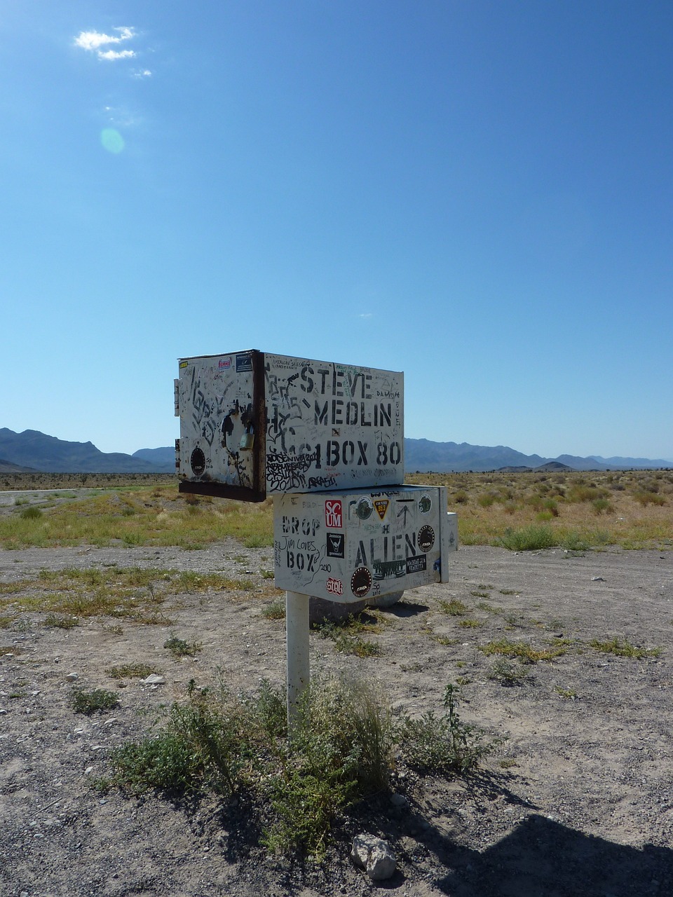 a sign sitting in the middle of a dirt field, by Stephen Gilbert, graffiti, alien desert, box, mexican standoff, old signs