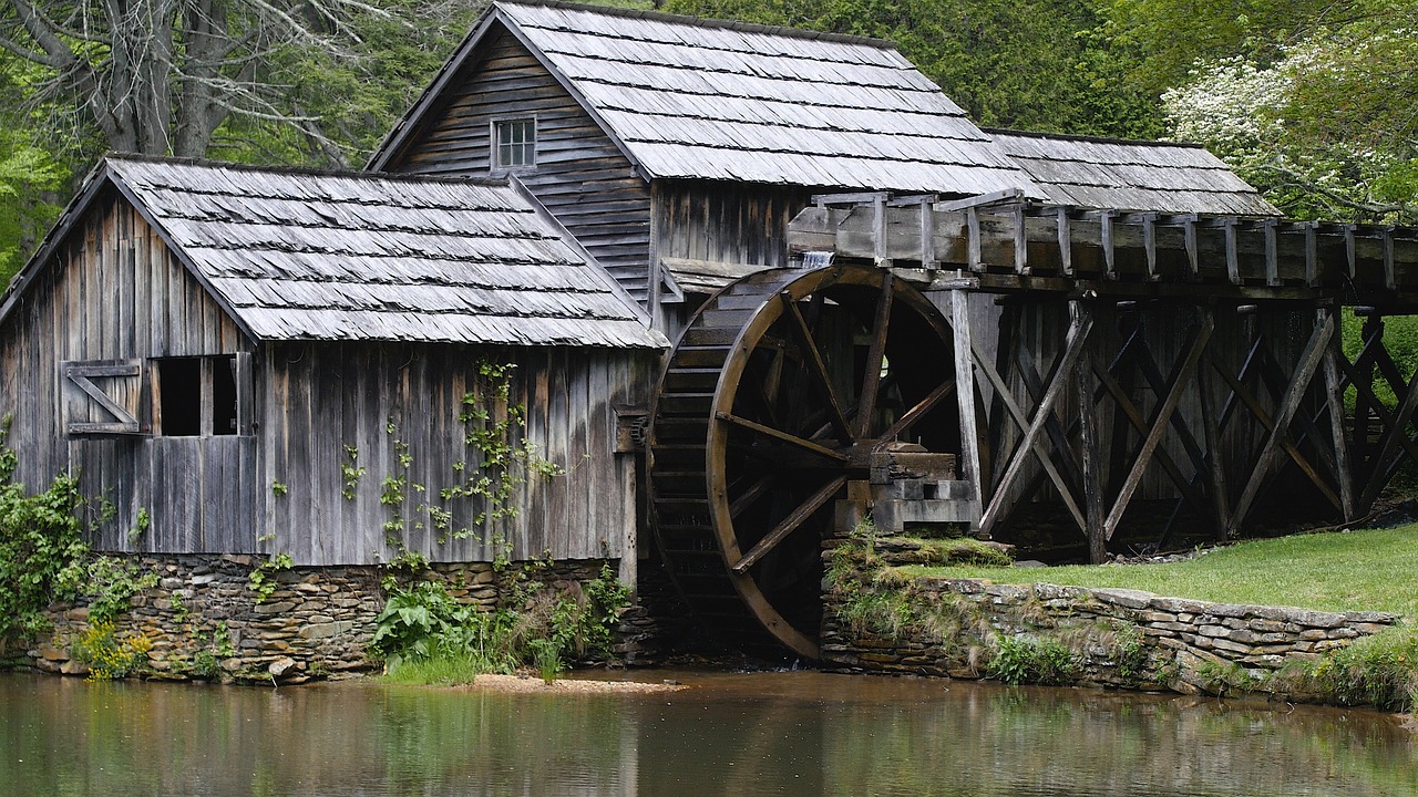 a wooden building with a water wheel in front of it, by John Hutchison, pixabay contest winner, he is from virginia, loosely cropped, photograph credit: ap, grain”