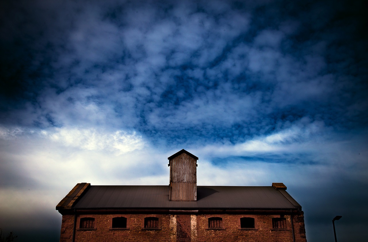 a large brick building with a clock tower, by Andrew Domachowski, minimalism, dramatic clouds, auschwitz camp, rock roof, post processed