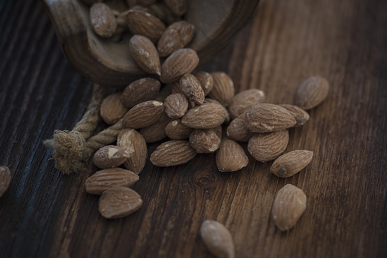 a wooden spoon filled with nuts on top of a wooden table, a picture, renaissance, background image, alessio albi, brown almond-shaped eyes, close-up product photo