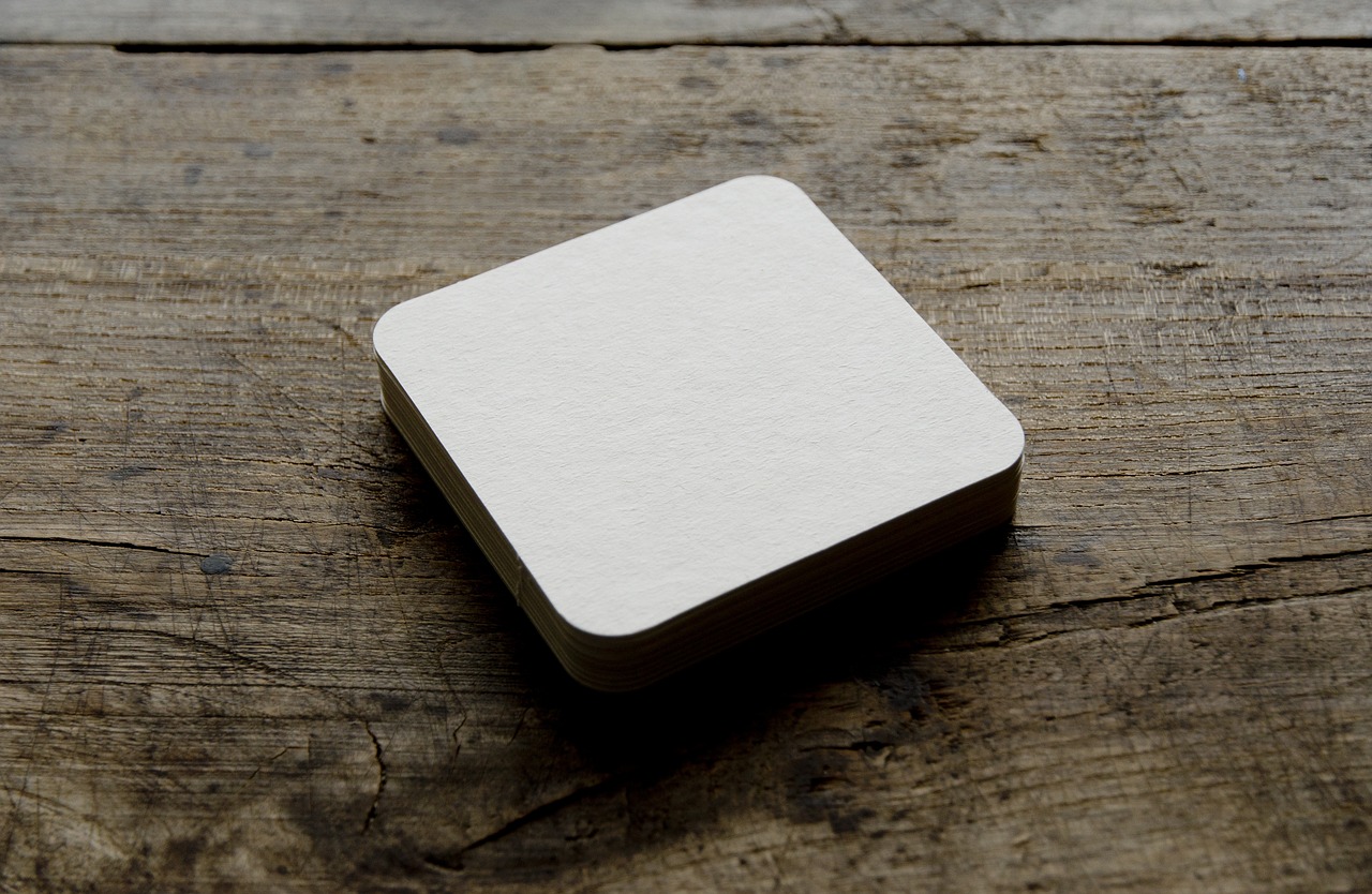 a white square sitting on top of a wooden table, by Simon Gaon, rounded corners, card template, soft pads, mill